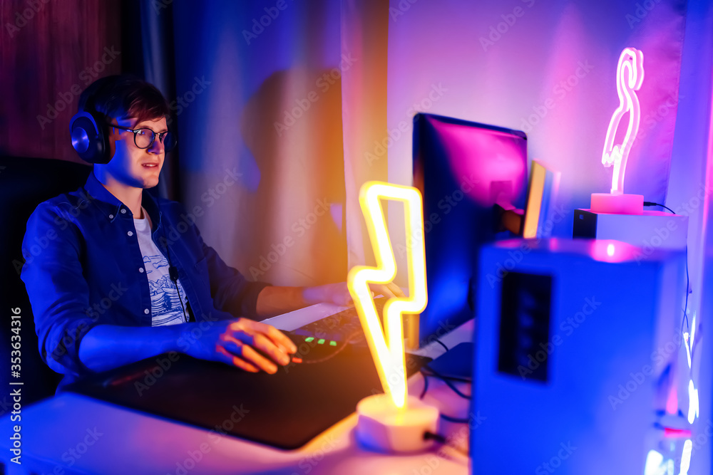 gamer playing video games on a computer with headphones and using a colorful backlit keyboard gamer playing video games on a computer with headphones and using a colorful backlit keyboard