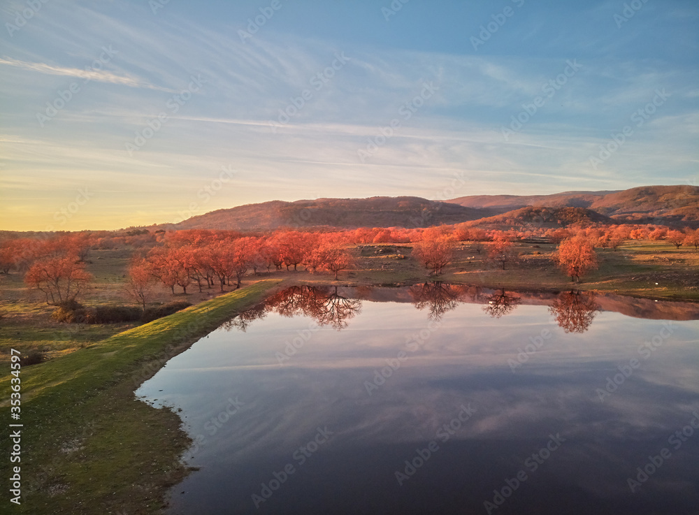 Aerial view of beautiful rural landscape at sunset with a lake and green meadows in autumn