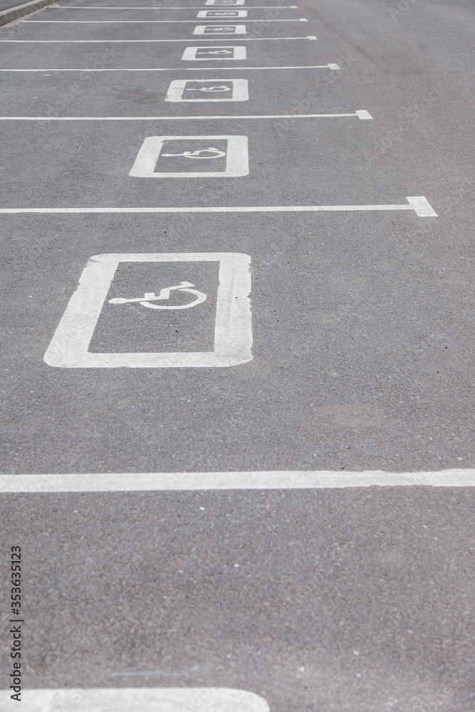 Parking For Persons With Disabilities. International symbol of disabled people drawn in white on Parking space of shopping center. Space for several cars with disabled drivers