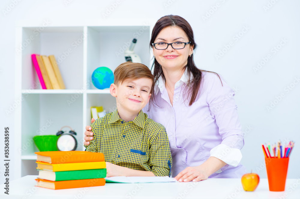 The child and teacher are sitting at the table in the classroom and are engaged in education. The child and teacher are sitting at the table in the classroom and are engaged in education.