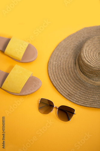 Straw hat chic eyeglasses and ohra flip flops on the orange background summer mood near seaside