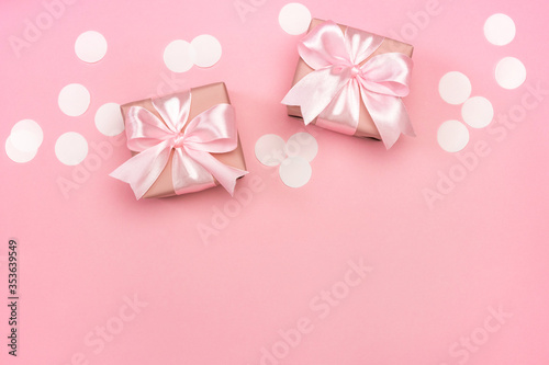 Two gifts or present boxes decorated with confetti on pink pastel background. Top view with copy space. Flat lay composition for birthday or wedding. 