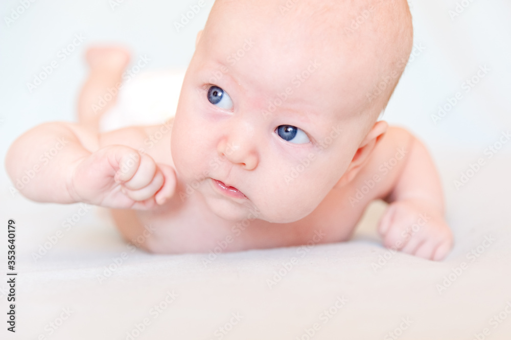 A smiling baby with blue eyes smiles and crawls on a blue sheet. A smiling baby with blue eyes smiles and crawls on a blue sheet.
