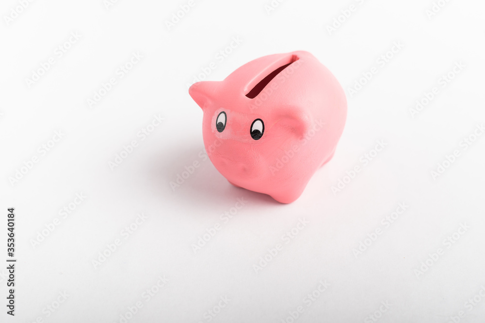 Side view of small pink piggy bank isolated on a white table, concept of saving for financial crisis or unemployment
