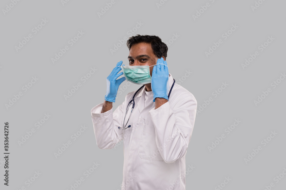Doctor Puts on Medical Mask Wearing Gloves Isolated. Indian Man Doctor Medical Uniform