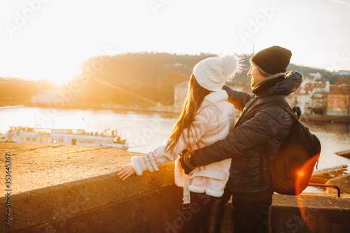 Stylish young couple looking into the distance while standing on a bridge at sunset