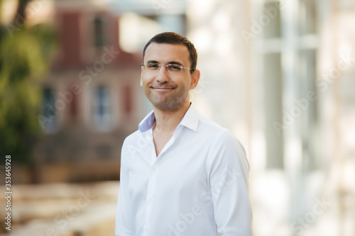 young man in shirt and glasses standing on city street