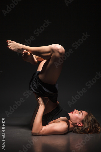 Young girl doing yoga on a black background