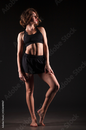 Young girl doing yoga on a black background © Denis