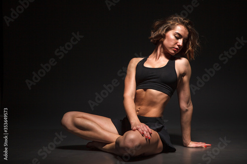 Young girl doing yoga on a black background