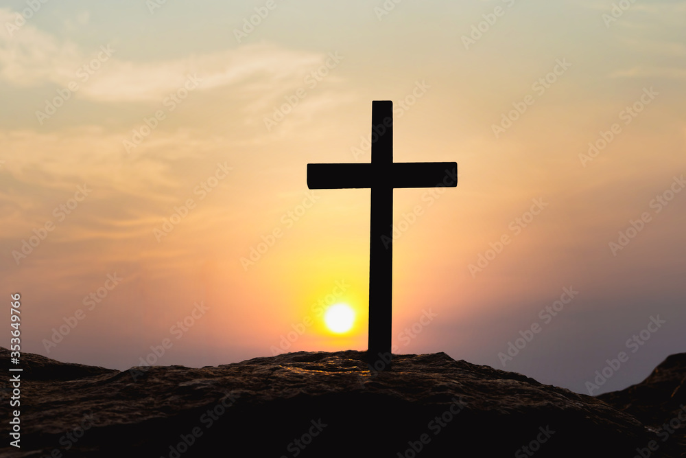 Silhouettes of crucifix symbol on top mountain with bright sunbeam on the colorful sky background