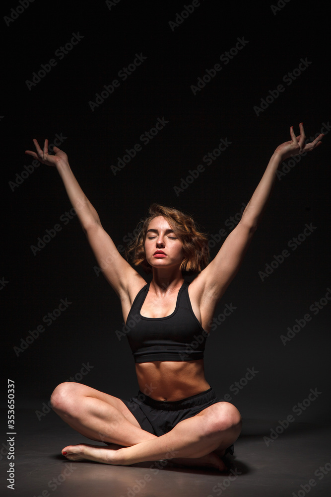 Young girl doing yoga on a black background