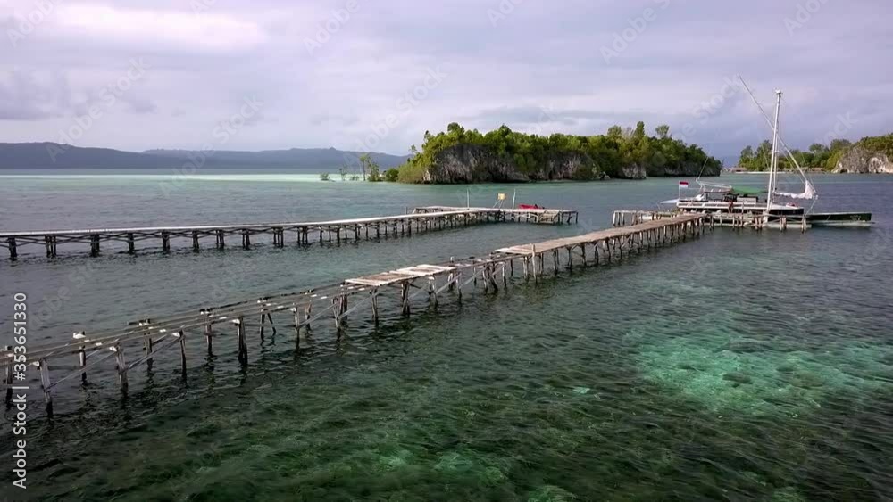 Broken pier in the Raja Ampat islands Indonesia with boat at the end displaying the Indonesian flag, Aerial pan right shot Broken pier in the Raja Ampat islands Indonesia with boat at the end displaying the Indonesian flag, Aerial pan right shot