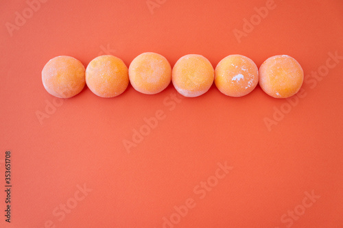 Mochi with mango. Premium ice-cream wrapped in sweet rice dough, traditional japonese desert. Gluten Free. Orange on pastel blue