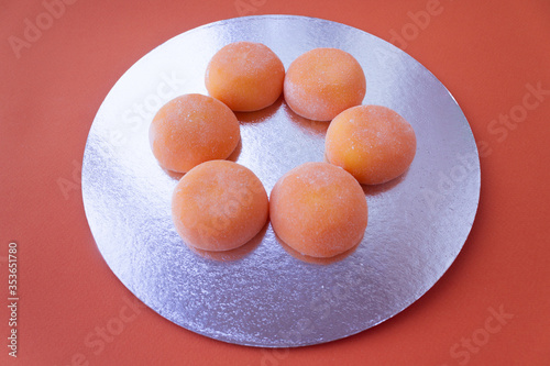 Mochi with mango. Premium ice-cream wrapped in sweet rice dough, traditional japonese desert. Gluten Free. Orange on pastel blue