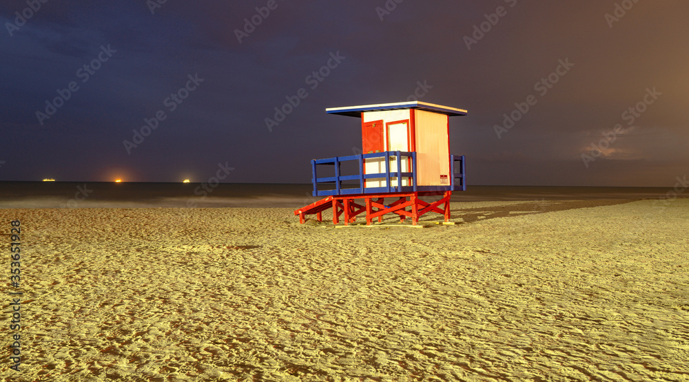 Fototapeta premium Lifeguard tower at night. A beautiful beach in Florida. Miami nightlife. Beautiful Miami Beach sand without people.