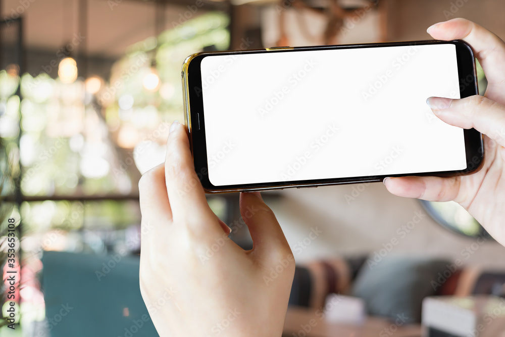 mock-up phone in hand holding on blur restanrant background with clipping path inside