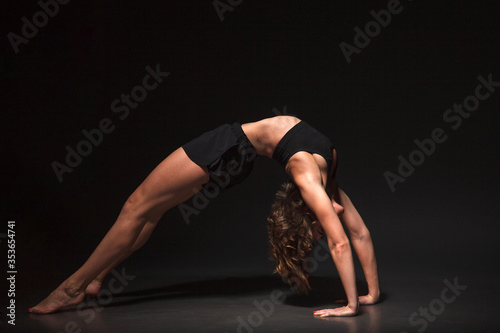 Young girl doing yoga on a black background