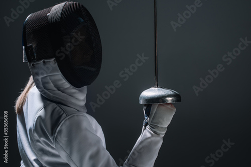 Back view of fencer holding rapier isolated on black