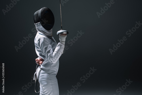Side view of fencer holding rapier isolated on black with copy space