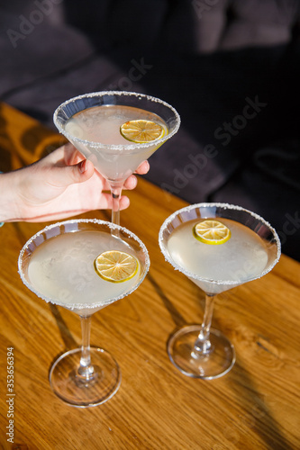 Classic Margarita cocktail with salted border on a wooden table with lemon and utensils