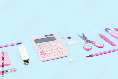 Assorted office and school pink and white stationery items on pastel background as border. Top view with copy space. back to school for girls or education and craft concept. Calculator and scissors