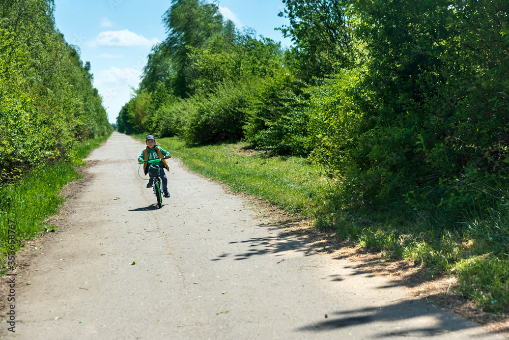 Boy on bicycle at summer asphalt road. Kid cycling outdoors. Summer sport activity concept. Soft focus