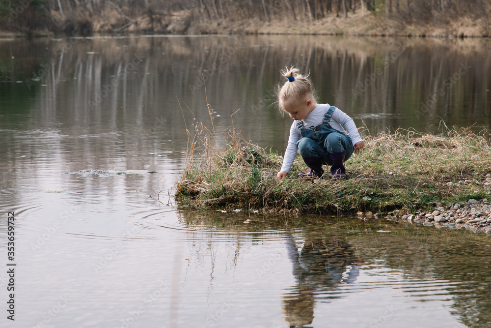 Little girl in rubber boots catches and feeds fish on the river in a jar Little girl in rubber boots catches and feeds fish on the river in a jar