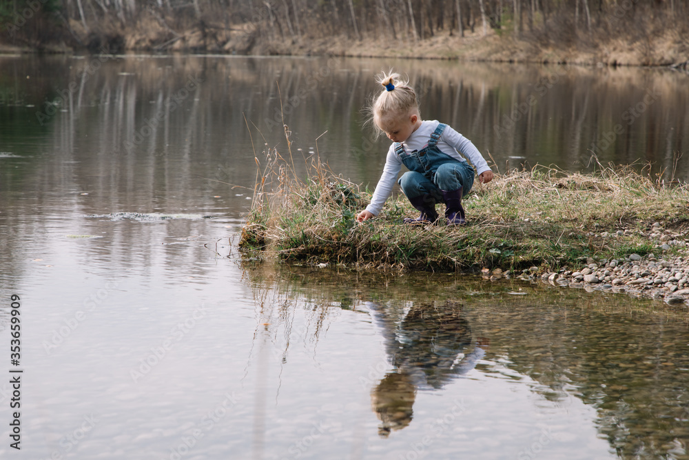 Little girl in rubber boots catches and feeds fish on the river in a jar Little girl in rubber boots catches and feeds fish on the river in a jar