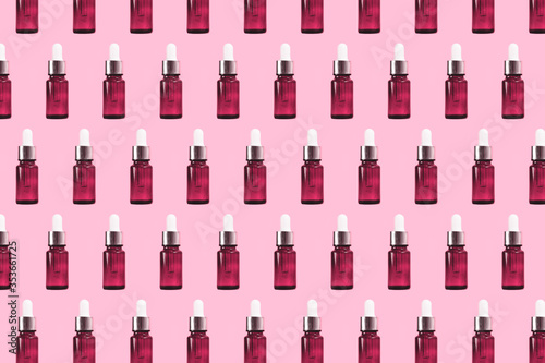 A glass dropper bottle on the pink background.