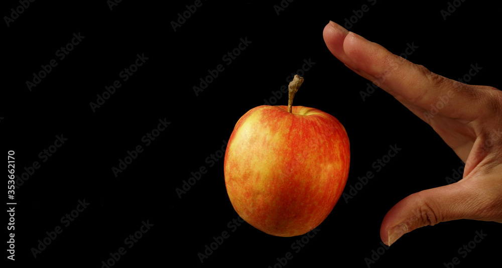 Hand and red apple on black background with levitation effect. Vegan Raw Food Concept Hand and red apple on black background with levitation effect. Vegan Raw Food Concept