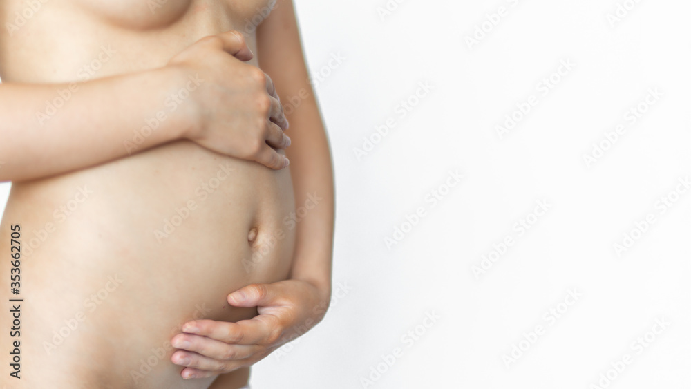 Pregnant woman hugs belly with two hands on a white background. Close-up. The health of a young mother, the health of the child, childbirth. Healthy pregnancy. Banner crop