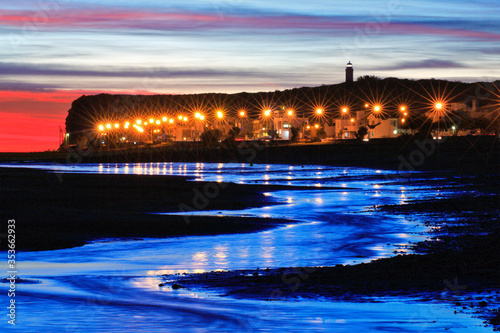 "El Condor" beach at sunset, with town lights, lighthopuse, and sea reflections. Rio Negro, Argentina