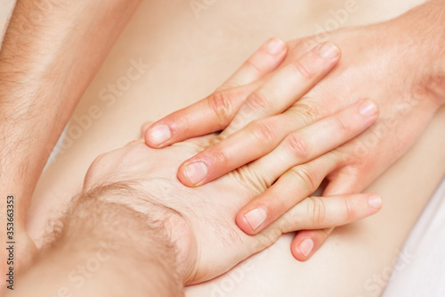 Woman receiving back massage with hands of male therapist.