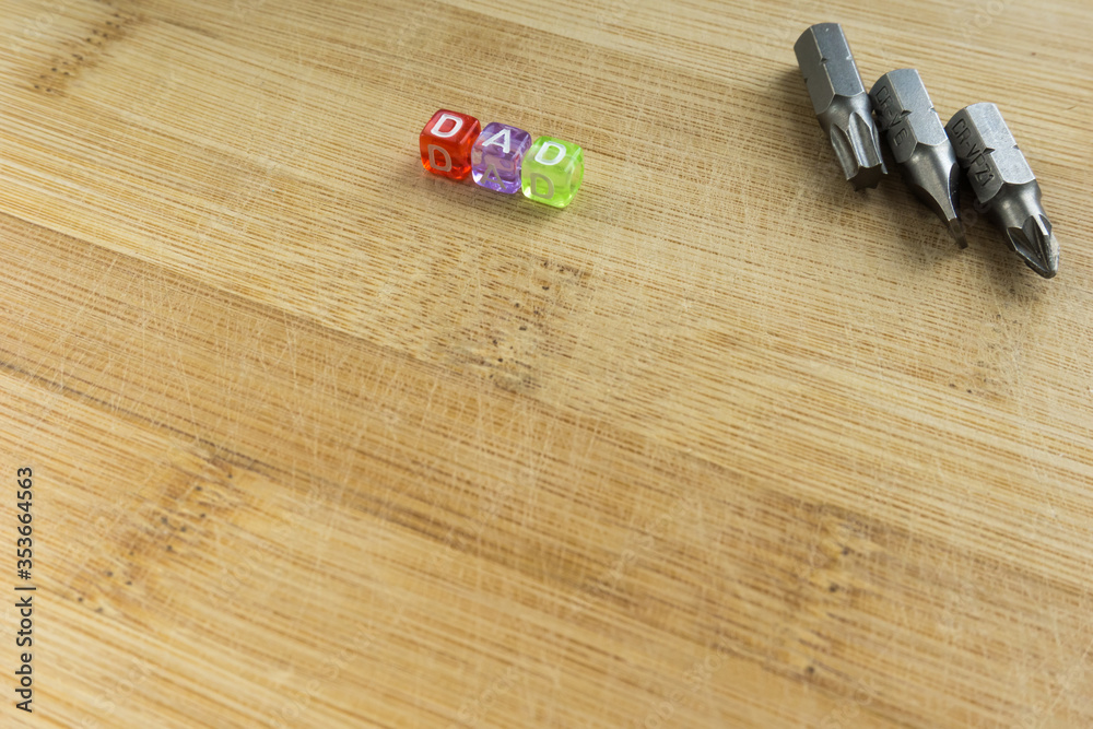 Toy cubes, beads with the inscription DAD on a wooden background with tools Toy cubes, beads with the inscription DAD on a wooden background with tools