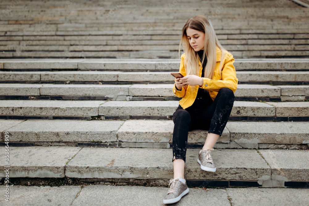 Young woman with the phone sitting on the stairs 