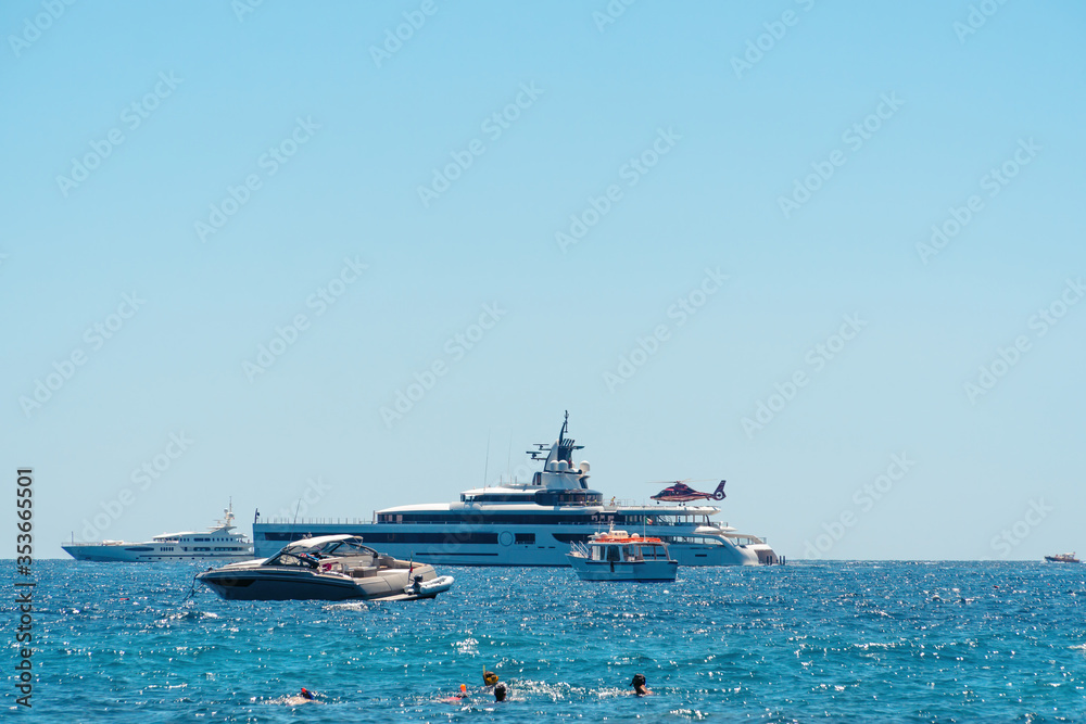 View from the shore, the bay with ships and boats. Luxury premium yacht, takes off landing aircraft, helicopter. Water transport. Rest and vacation in the ocean. Beach.
