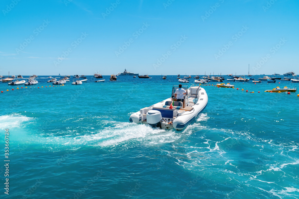 Naklejka premium A small watercraft begins to move. Light motor boat. Inflatable boards. Sunny summer day. The concept of renting a ship and touristic excursions. Fishing and movement.
