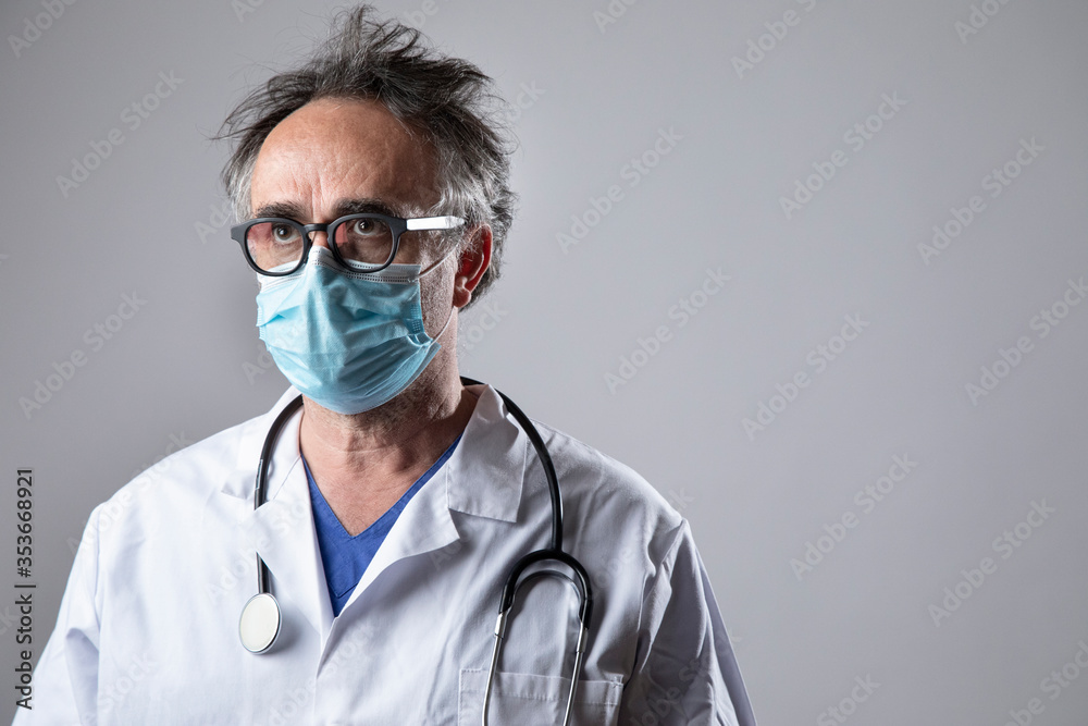 medico in camice bianco spettinato e con aria stranita con fonendoscopio al collo, isolato su sfondo medico in camice bianco spettinato e con aria stranita con fonendoscopio al collo, isolato su sfondo