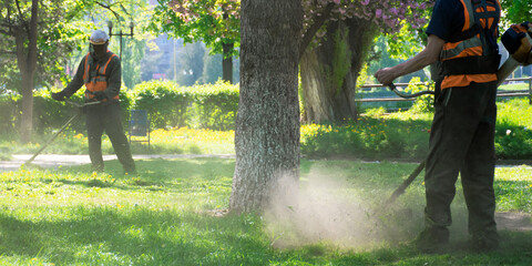 Leinwandbilder Khaki professional garden service at work. lawn care concept. cutting an mowing grass in the park. spring summer season  © Pellinni