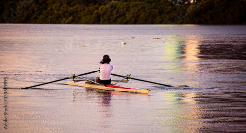 A woman takes an early morning workout rowing on a river.