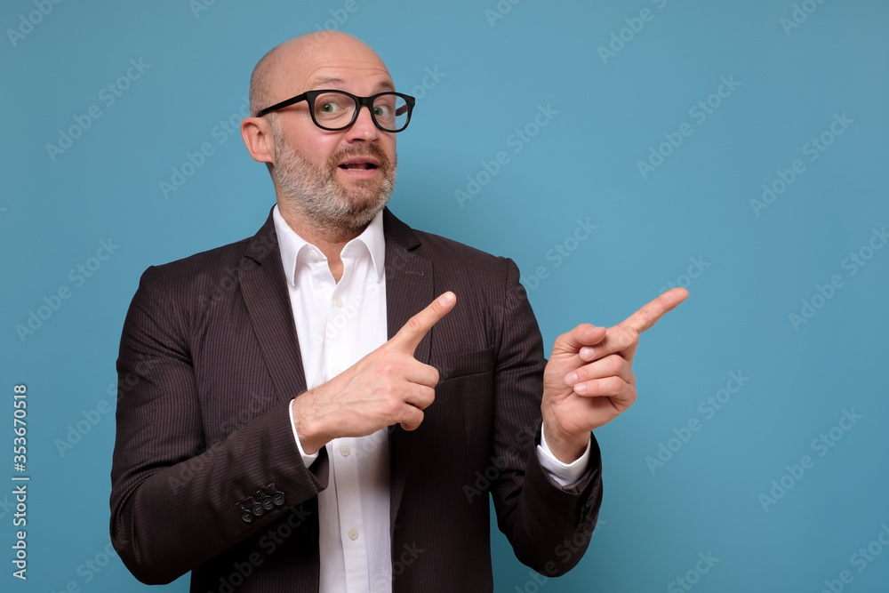 Mature italian business man in suit and glasses pointing on important information aside. Studio shoot