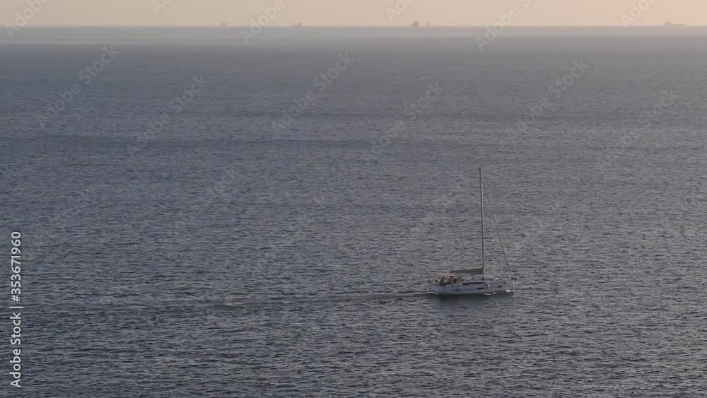 Luxury sailing yacht moving fast alone in deep blue sea during sunset. Horizon skyline in background Luxury sailing yacht moving fast alone in deep blue sea during sunset. Horizon skyline in background