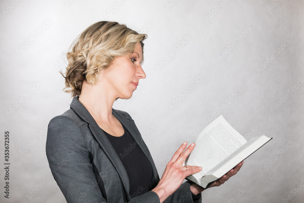 Business lady with glasses posing in a studio in a good mood with a book in her hands Business lady with glasses posing in a studio in a good mood with a book in her hands