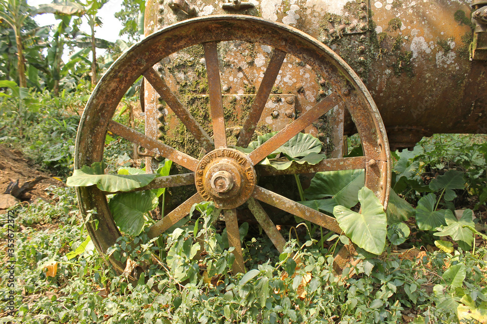 Detail of a metal wheel in a old abandoned machine of colonial time in ancient agricultural farm of Roça Sundy, in the northwest of the island of Príncipe, São Tomé and Príncipe Detail of a metal wheel in a old abandoned machine of colonial time in ancient agricultural farm of Roça Sundy, in the northwest of the island of Príncipe, São Tomé and Príncipe