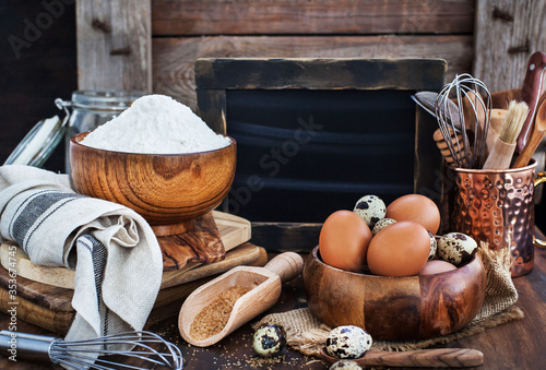 Baking ingredients and blackboard on background, wooden rustic style