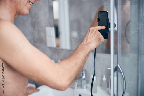 Contented man using his smartphone in a bathroom