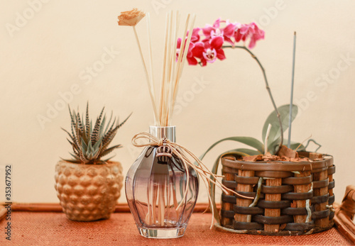 Aromatic air freshener in color transparent glass bottle and flower