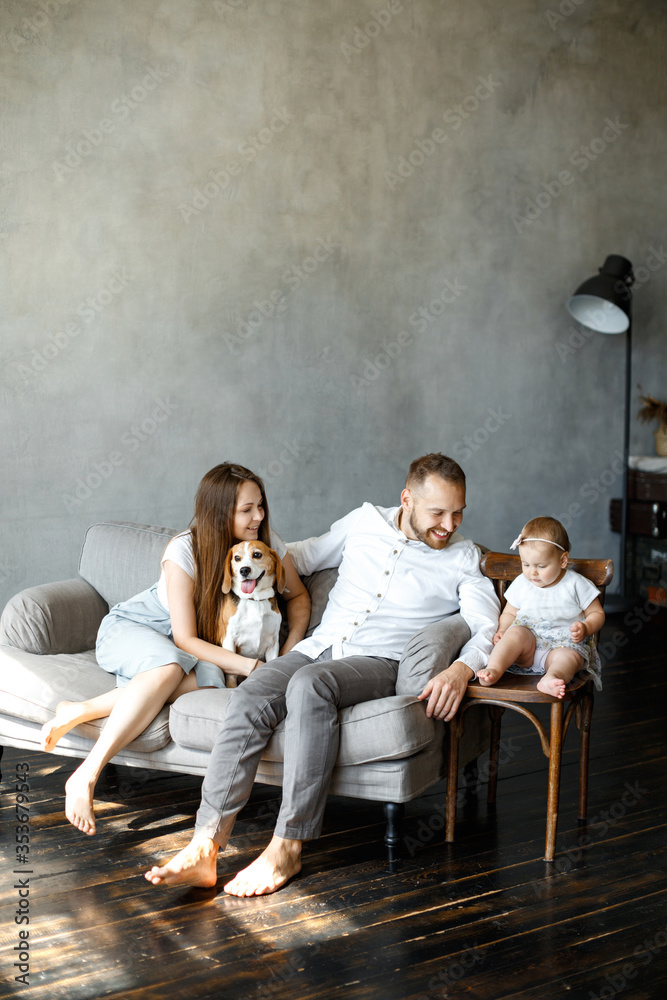 Naklejka premium Happy family spend time together at home. Parents, little daughter and beagle dog together. Happy family concept