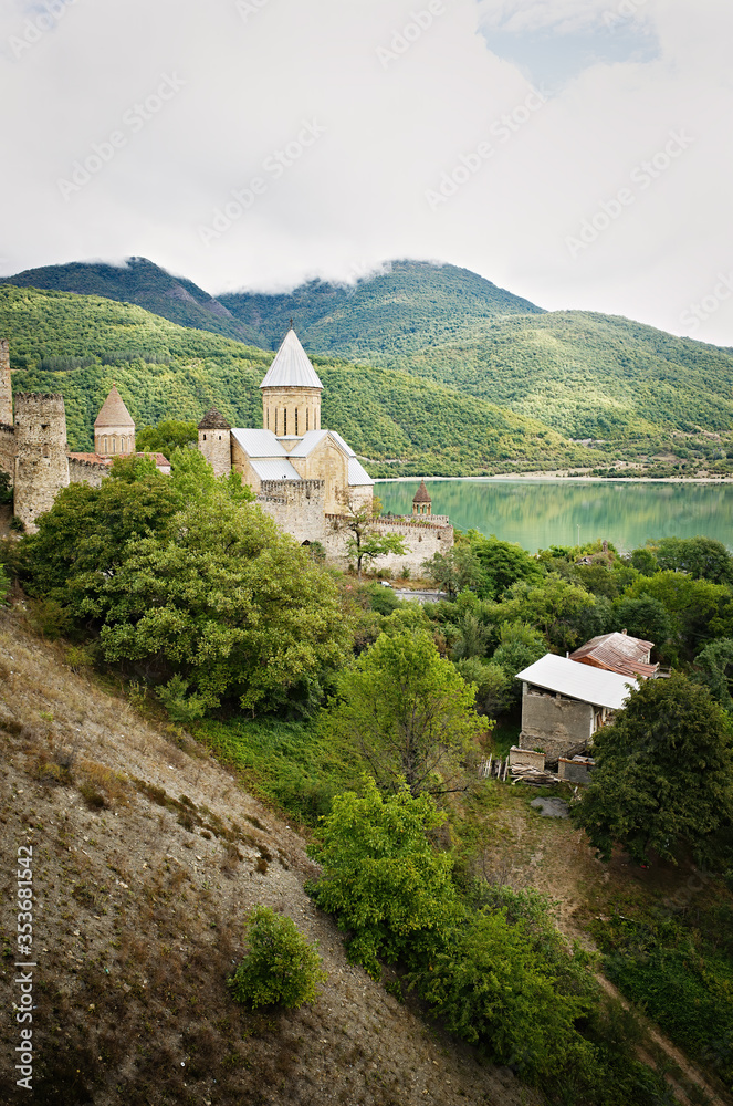 Georgian Cathedral. On the shore of the reservoir, lake. Against the backdrop of a mountain landscape.